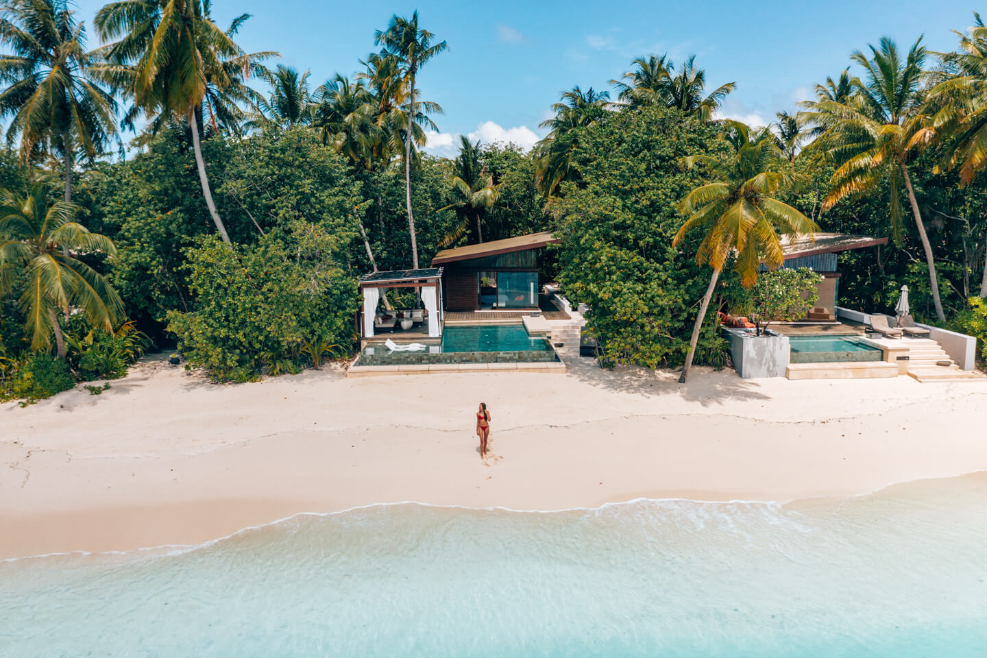 empty beach with villa, palm trees and blue water