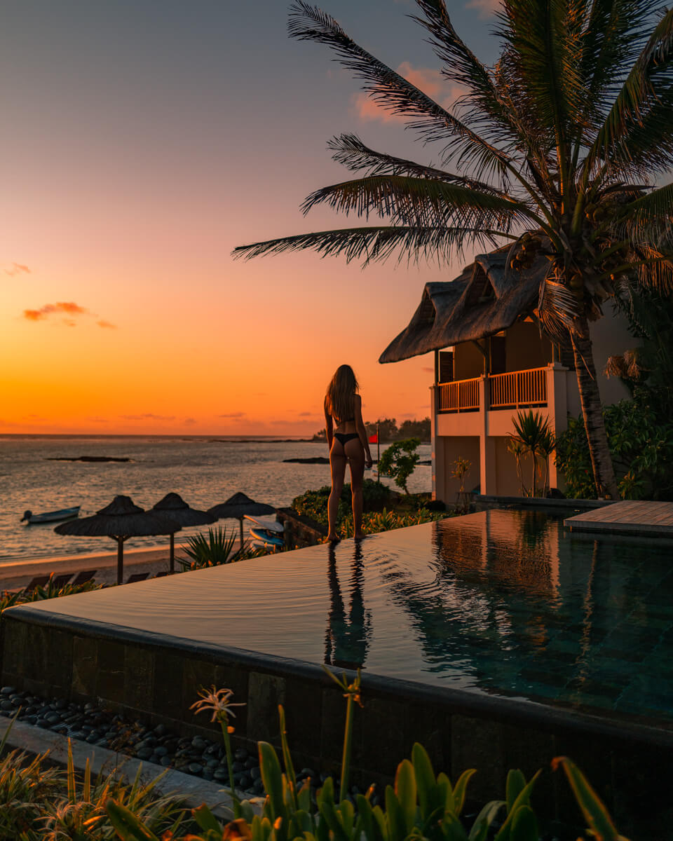 girl standing at the edge of a pool at the C Mauritius resort, overlooking the sunrise