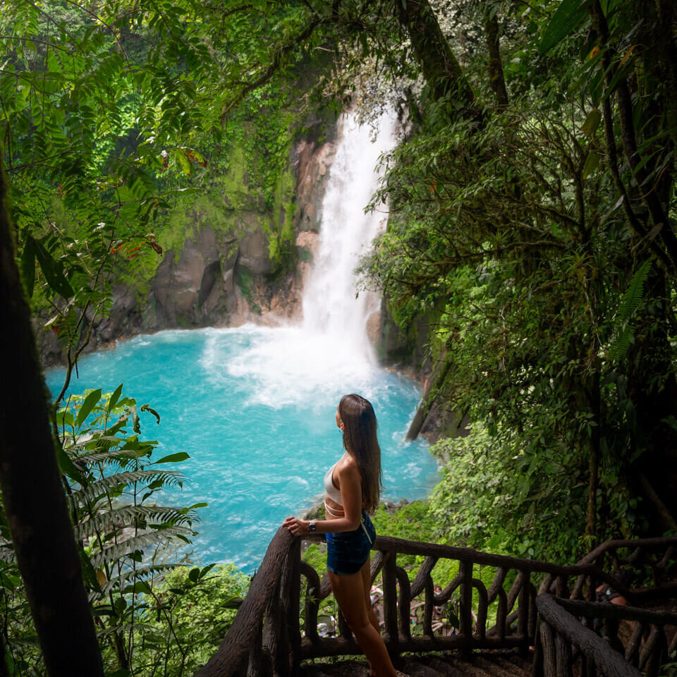 the Rio Celeste Waterfall in Costa Rica with blue water, a staircase leading down to the waterfall