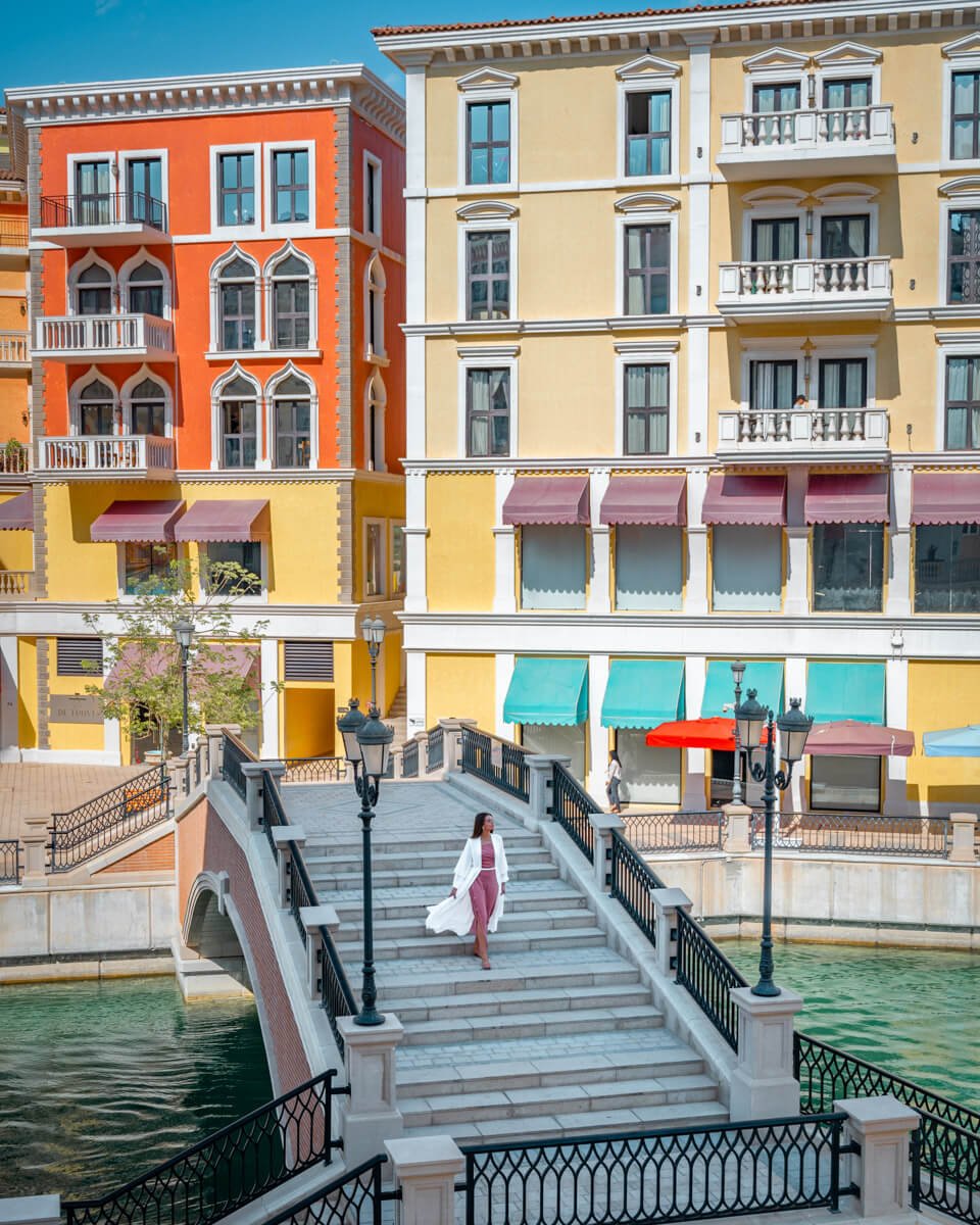 a bridge leading over a canal in front of colorful buildings at the Qanat Quartier in Doha Qatar